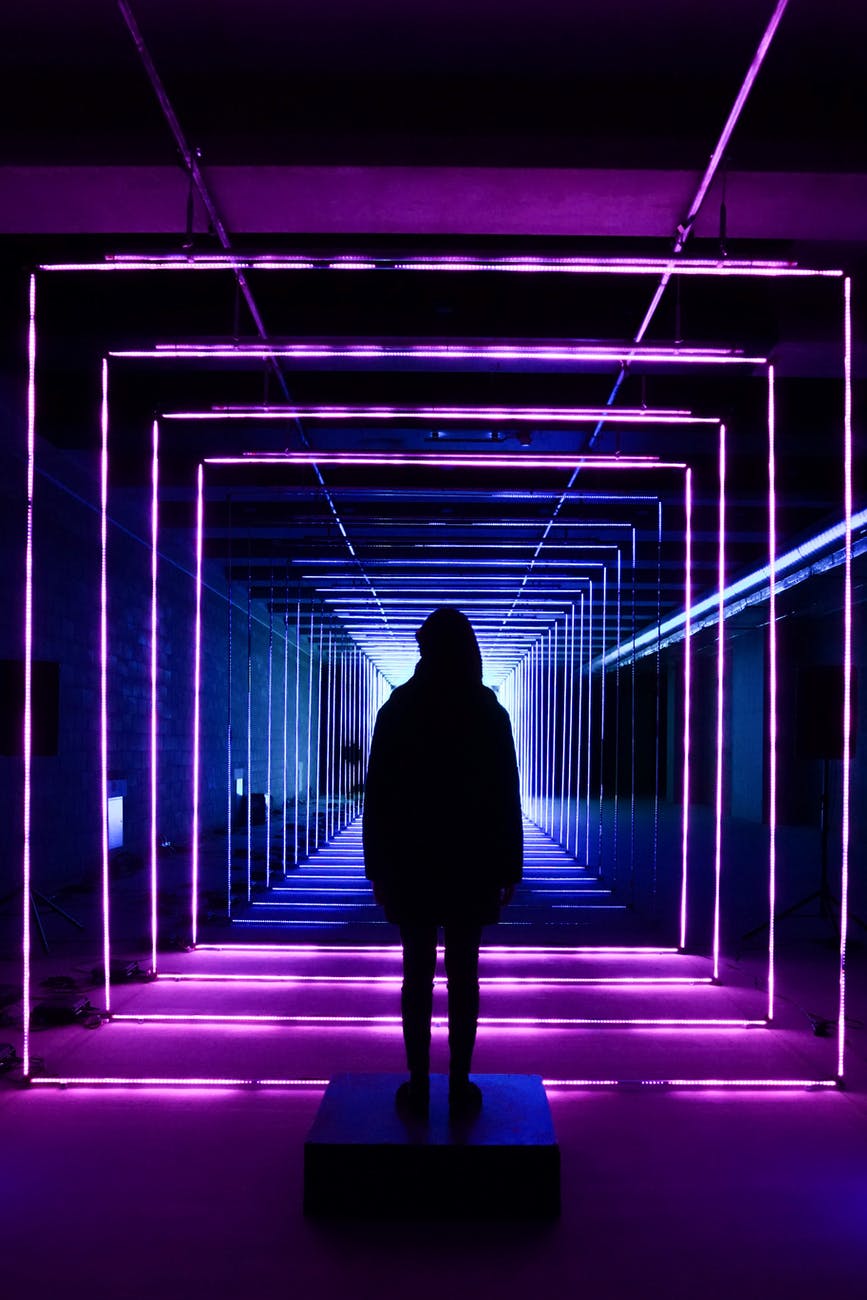 silhouette photo of person standing in neon lit hallway